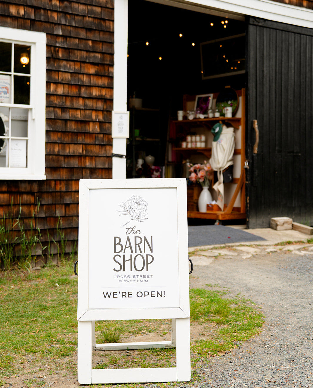 The Barn Shop sign in front of a wooden building with an open door.
